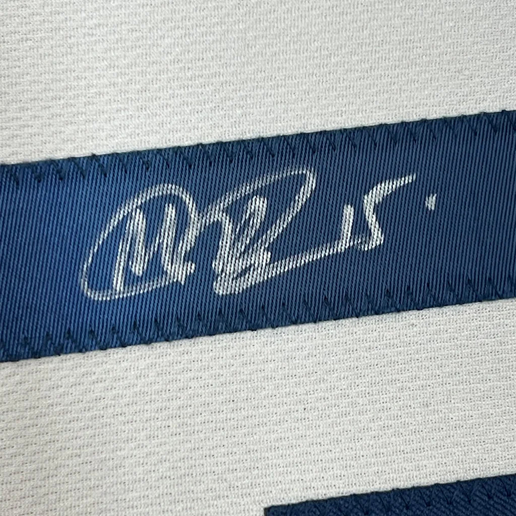 Blue woven label with white embroidered signature on framed Megan Rapinoe USA World Cup jersey