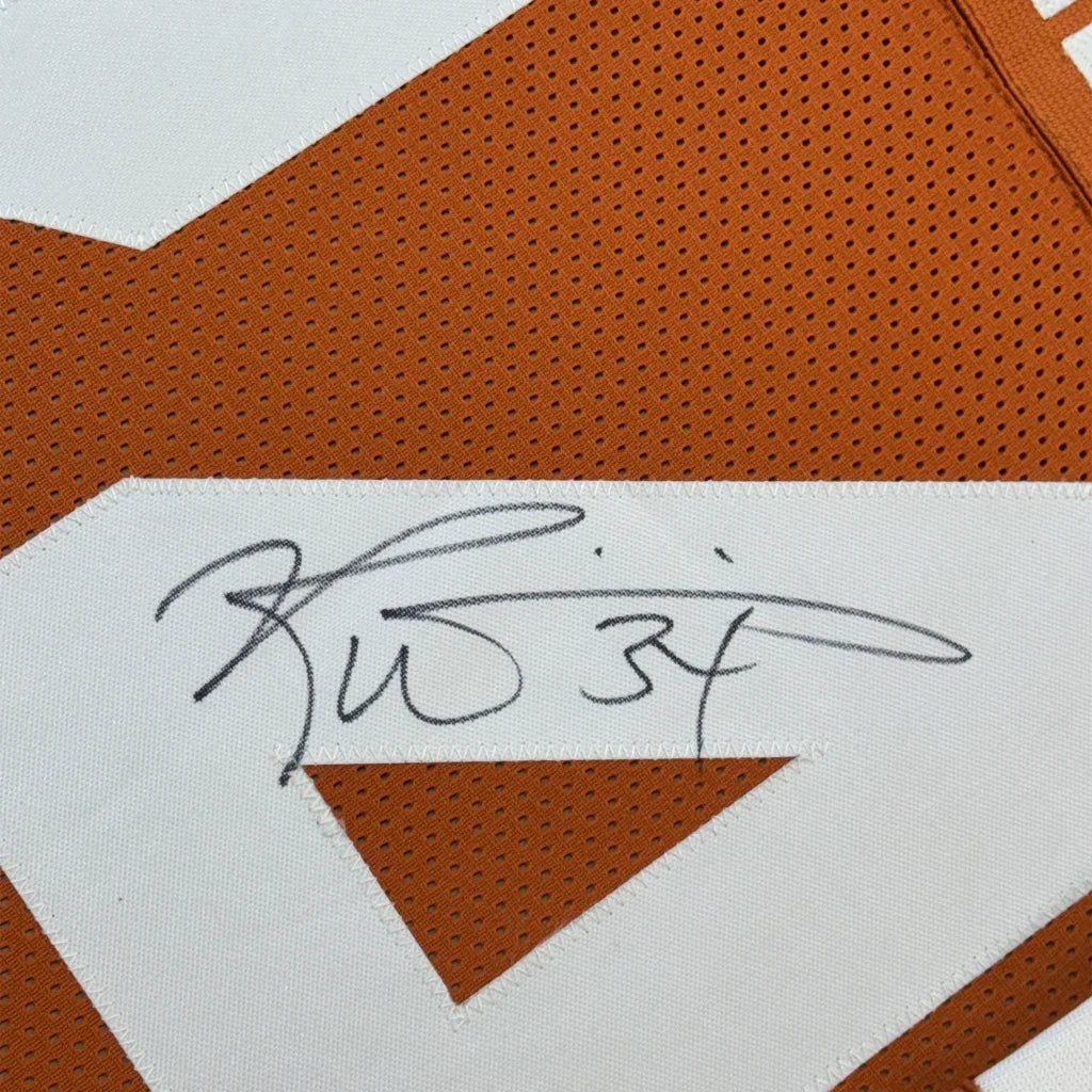 Orange and white signed football jersey with player photos in a frame