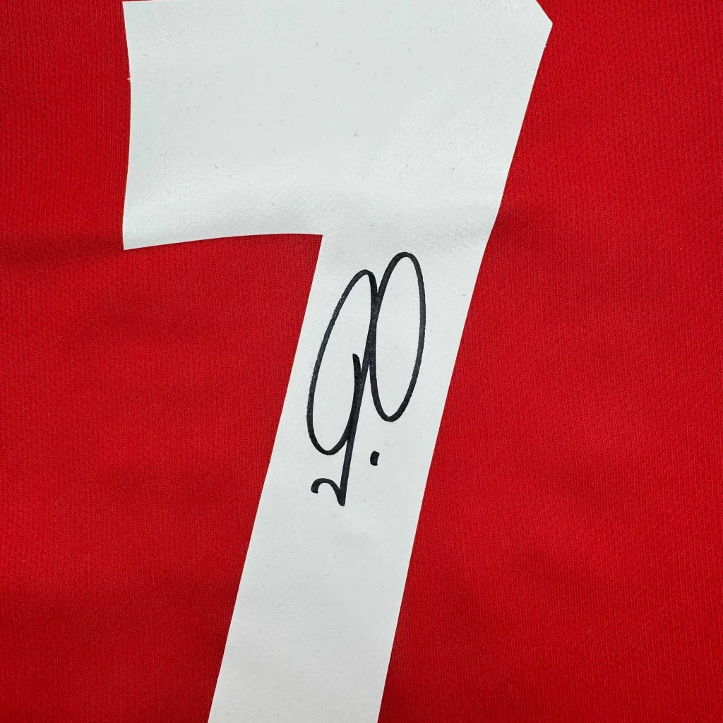 Red fabric with a white diagonal stripe on a framed Robert Pires Arsenal jersey ready to hang