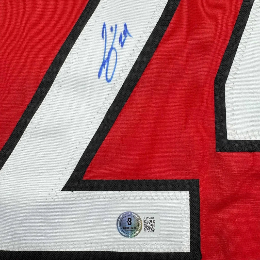 Red sports jersey with white number and blue autograph, professionally framed for man cave