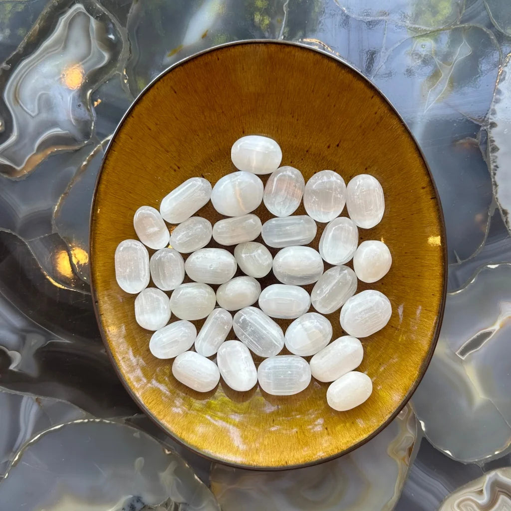 Smooth translucent selenite stones in amber bowl for collection