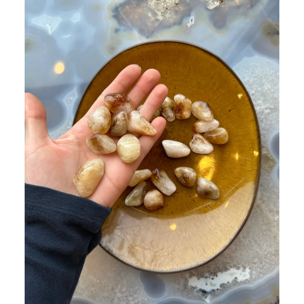 Hand holding gorgeous tumbled citrine stones in amber hues
