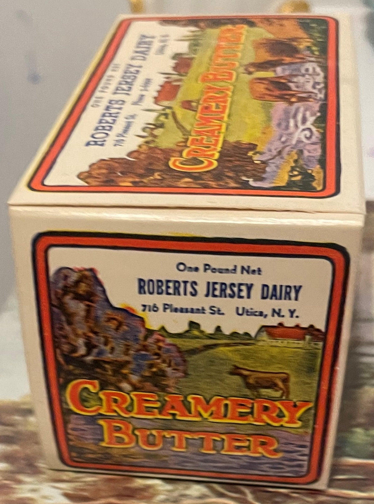 Vintage cream box labeled "Roberts Jersey Dairy Creamery Butter" from Utica, N.Y., showing pastoral landscape with cattle