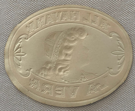 Oval embossed coin or medallion showing profile of woman's head in relief, with text around border in Cyrillic script, displa