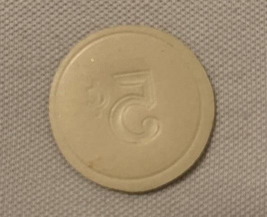 Cream-colored round embossed token with number 5 and decorative scrollwork, photographed flat on textured fabric background