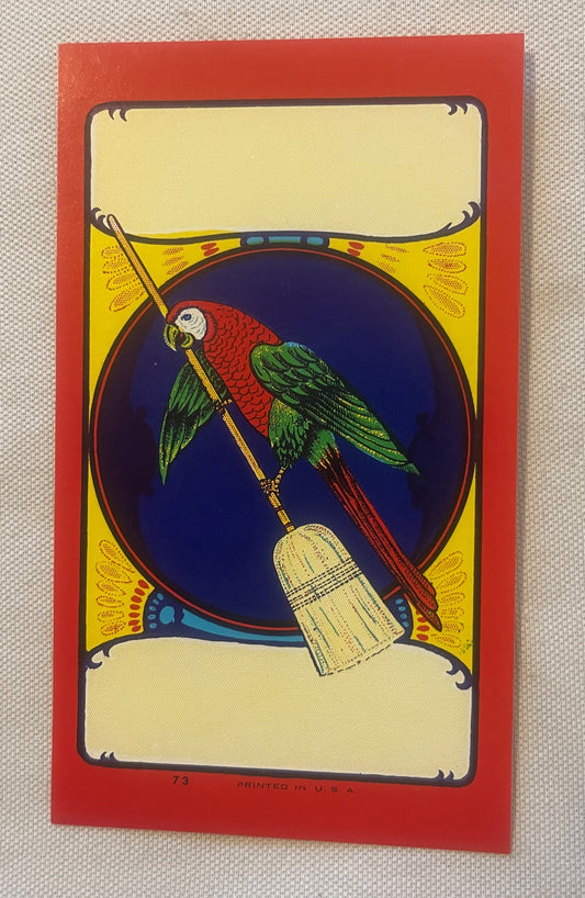 Vintage broom label with red border featuring a colorful macaw holding a paintbrush against a dark blue oval, yellow corners,