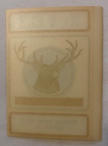 Tan paper label with embossed elk head in circle, three rectangular text boxes, vintage broom maker's label