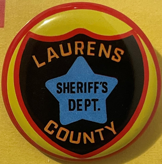 Circular tin badge with red outer rim and yellow inner ring, black center panel featuring blue star with "SHERIFF'S DEPT." te