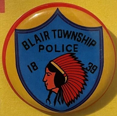 Vintage Blair Township Police tin litho badge featuring a Native American chief profile in red headdress on blue shield with