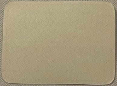 Blank cream-colored vintage label with rounded corners, displayed flat on textured fabric background