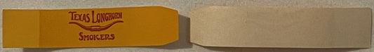 Yellow cigar band with red "Texas Longhorn Smokers" text, photographed at an angle against gray background