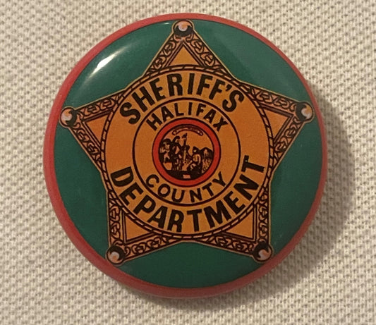 Vintage sheriff's badge pin with gold star on green and red circular tin background, reading "Sheriff's Halifax County Depart