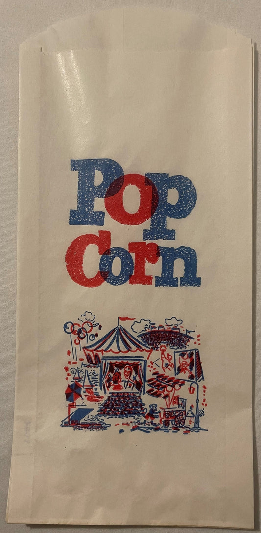 Front of the 1950s circus popcorn bag: POP CORN in speckled blue and red letters above a midway scene with a striped big top