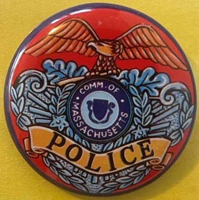 Vintage tin litho police badge featuring red eagle, blue laurel wreaths, and "Commonwealth of Massachusetts Police" text on y