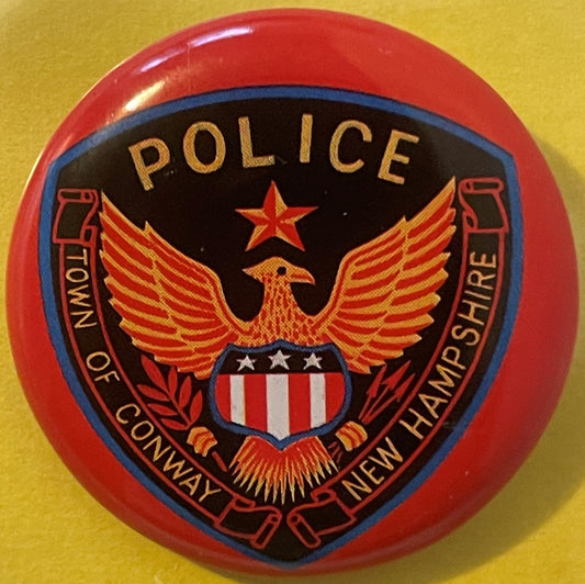 Vintage tin litho police badge with red rim, black and blue shield, gold eagle, star, and shield emblem on yellow background.