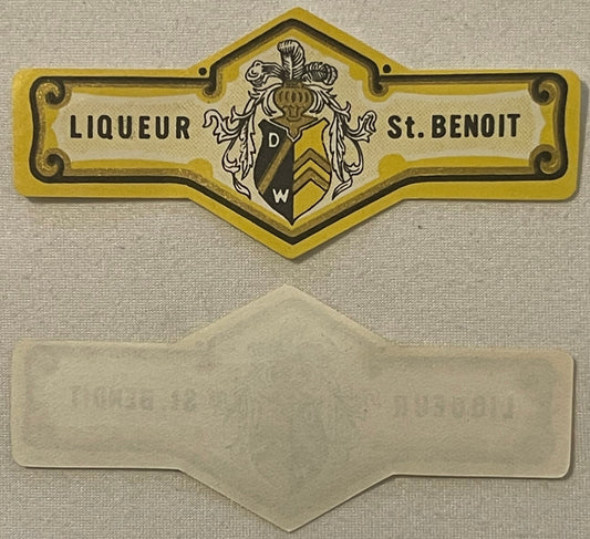Vintage yellow-gold liqueur label with "Liqueur St. Benoit" text and ornate heraldic crest, shown with blank reverse side bel