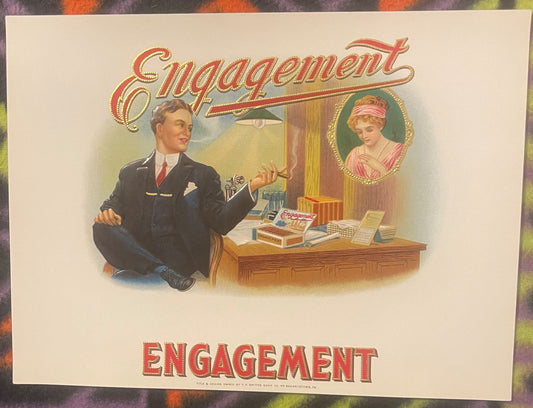 Antique embossed cigar label titled "Engagement" featuring a man at a desk and woman's portrait in ornate frame, cream backgr