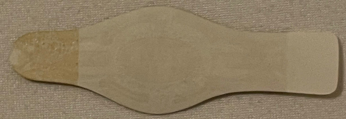 Cream-colored embossed cigar band with curved edges on textured beige fabric background