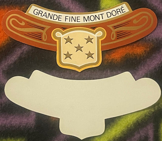 Ornate vintage wine label with orange wings, gold shield bearing five stars, and cream-colored blank banner on colorful textu
