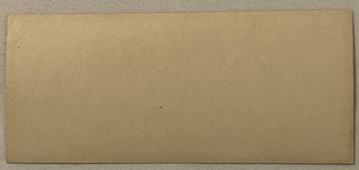 Blank cream-colored rectangular cigar label on gray fabric background, showing slight wear and minor dark spots