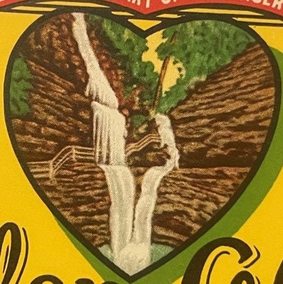 Heart-shaped beer label featuring a waterfall between rocky cliffs, green foliage, yellow background, Glen Ale branding visib