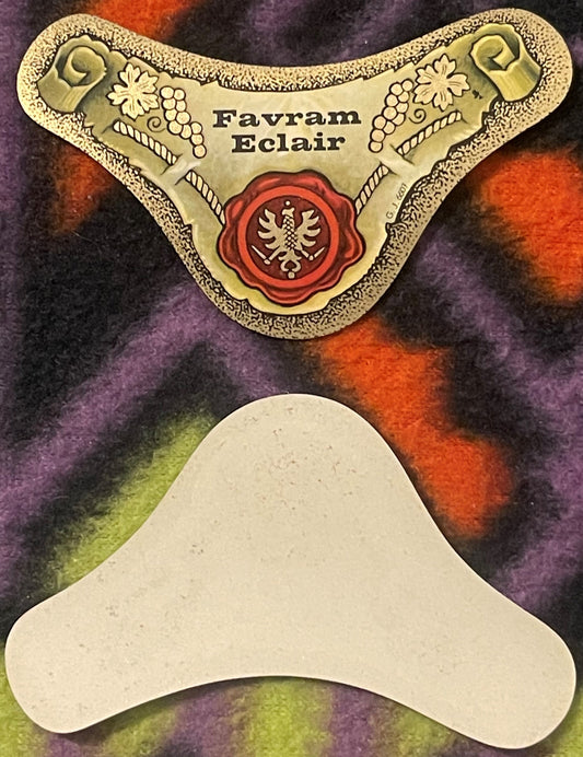 Vintage Favram Eclair wine neck label with ornate gold-embossed design, red wax seal crest, and decorative grape and floral motifs, displayed flat with blank cream-colored backing.