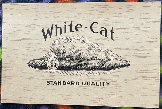 Vintage "White-Cat" cigar box label on cream wood-grain background featuring black-ink illustration of fluffy cat on cigar wi