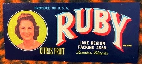 Vintage Ruby brand citrus fruit crate label featuring a woman's portrait in yellow circle and red lettering on dark blue back