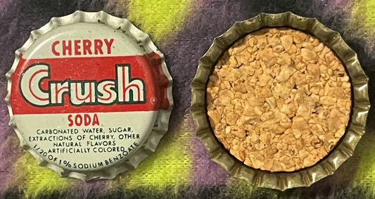 Vintage Cherry Crush soda bottle cap showing red and white label with ingredients text, displayed flat next to its cork liner
