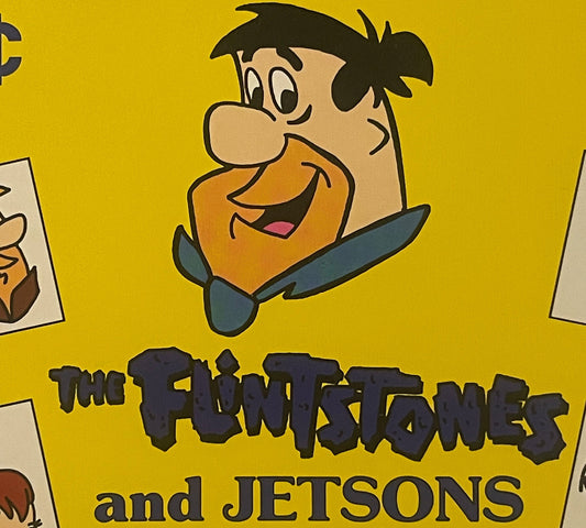 Vintage yellow vending display sign featuring Fred Flintstone character above "The Flintstones and Jetsons" text in black let
