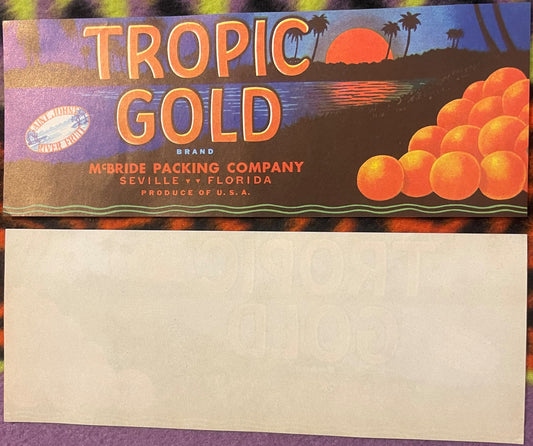 Vintage Tropic Gold citrus crate label featuring orange text on blue background with tropical sunset scene and oranges, McBri