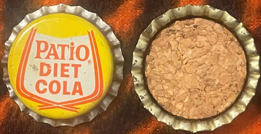 Vintage Patio Diet Cola bottle cap showing yellow front with orange text and tan cork back, displayed against rustic surface
