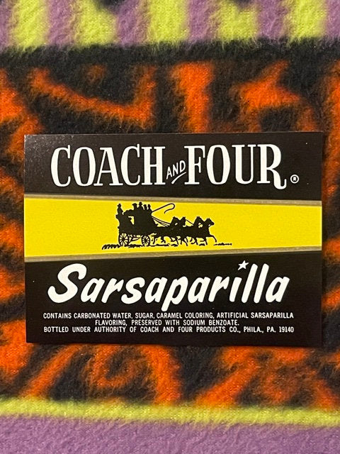 Vintage Coach and Four Sarsaparilla soda label on colorful striped fabric background, showing black banner with horse-drawn c