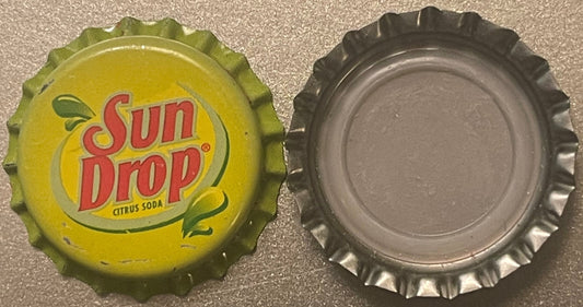 Vintage Sun Drop citrus soda bottle cap shown front and back; yellow side displays red logo with green leaf, silver reverse s