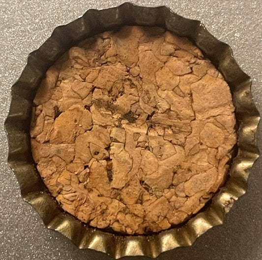 Vintage bottle cap with ridged metal rim and cork-lined interior showing tan and brown coloring, viewed from above on gray