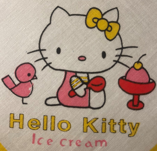 Vintage Hello Kitty cotton napkin with yellow bow and ice cream design printed on cream fabric, close-up flat lay view.