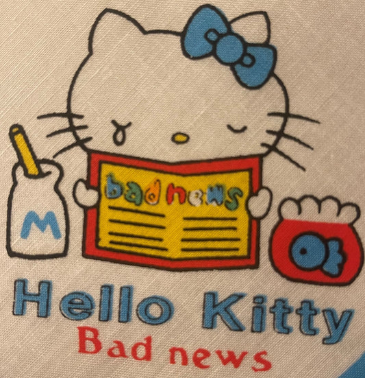 Vintage Hello Kitty cotton napkin with blue bow, holding newspaper, shown flat on beige fabric background