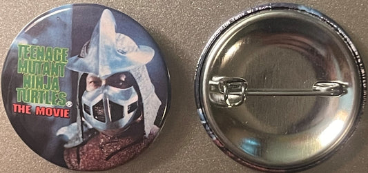 Front and back of a circular pinback button featuring Shredder from Teenage Mutant Ninja Turtles The Movie, with green text l