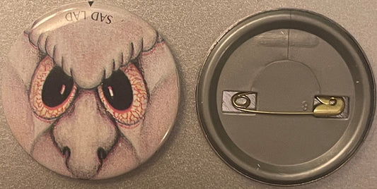 Vintage pin-back button showing front and back: front features illustrated sad creature with large bloodshot eyes and droopy