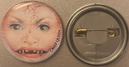 Front and back of vintage button pin featuring grotesque face with green eyes, veins, and fanged mouth; text reads "CREEP QUE