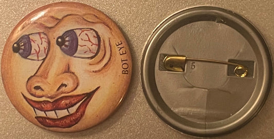 Front and back of a pin-back button featuring a grotesque face with bulging purple eyes, red veins, and a wide grin, with "BO