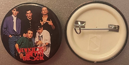Front and back of a circular pinback button featuring five young men in casual 1980s clothing with "NEW KIDS ON THE BLOCK" te