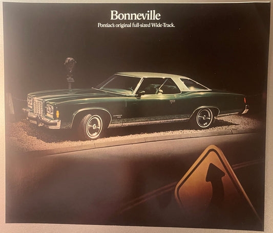 1974 Pontiac Bonneville dealer brochure cover featuring dark green sedan with hood stripes, Pontiac logo, and Indian head scu