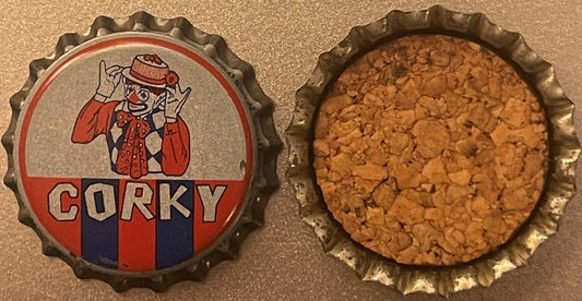 Vintage Corky the Clown bottle cap showing front with red and blue design and back cork lining, displayed side by side on tan