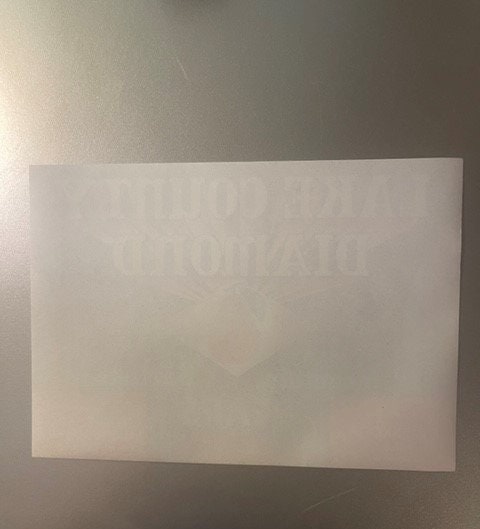 Blank cream-colored vintage crate label photographed flat against a gray wall, showing faint watermark text