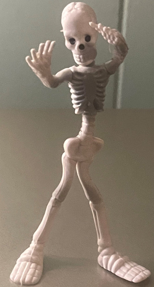 Cream-colored bendable skeleton figure with articulated joints, skull head with dark eye sockets, standing pose with arms rai