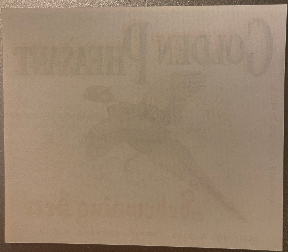 Vintage beer label with embossed Golden Pheasant branding visible against cream-colored paper, photographed flat