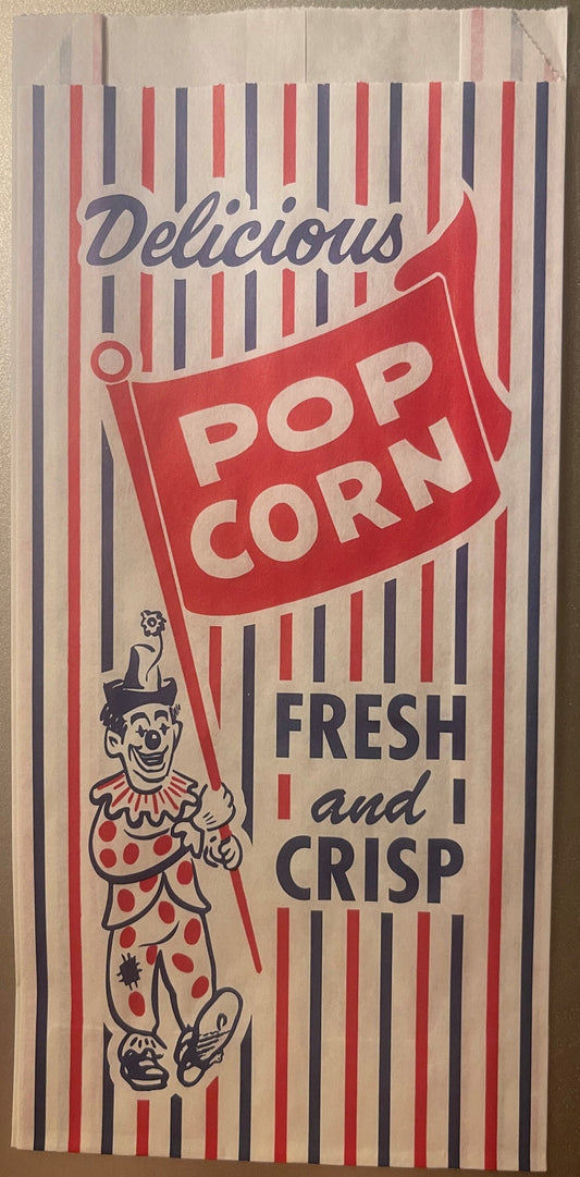 Vintage popcorn bag with red and blue striped design, smiling clown illustration, and text reading "Delicious Pop Corn" and "