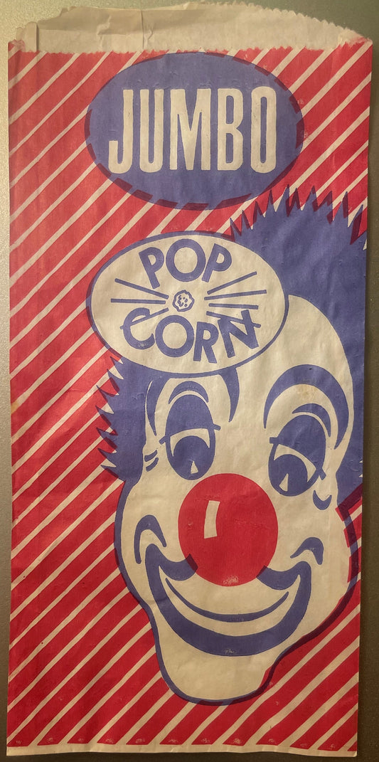 Vintage paper popcorn bag with red and white diagonal stripes, blue clown face with red nose, and "JUMBO POP CORN" text, laid