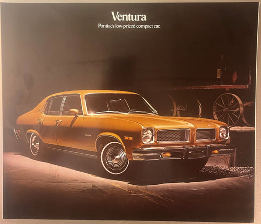 Golden-brown 1974 Pontiac Ventura sedan photographed in studio lighting against dark background with vintage farm equipment,
